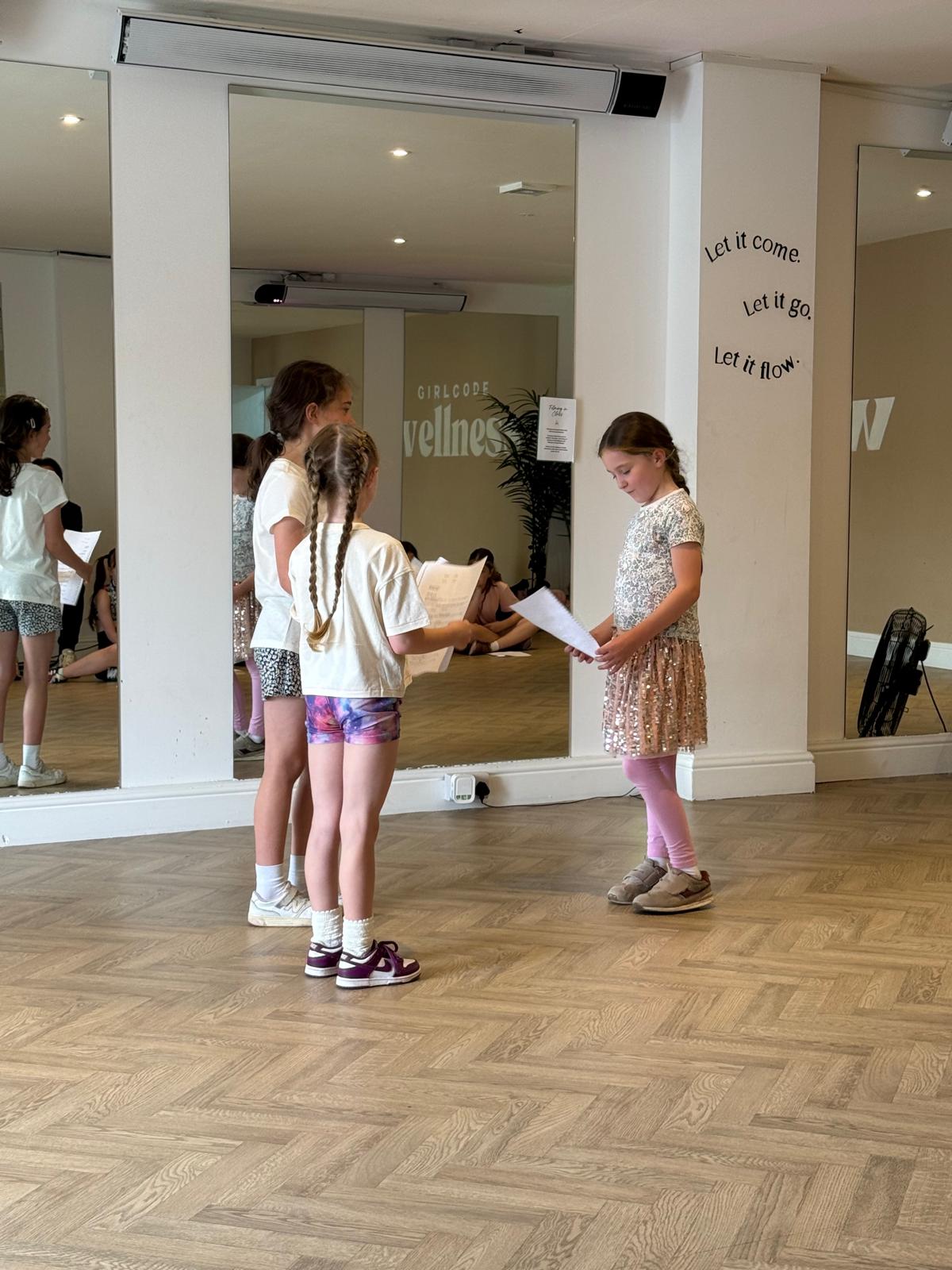Young performers rehearsing a scene with scripts